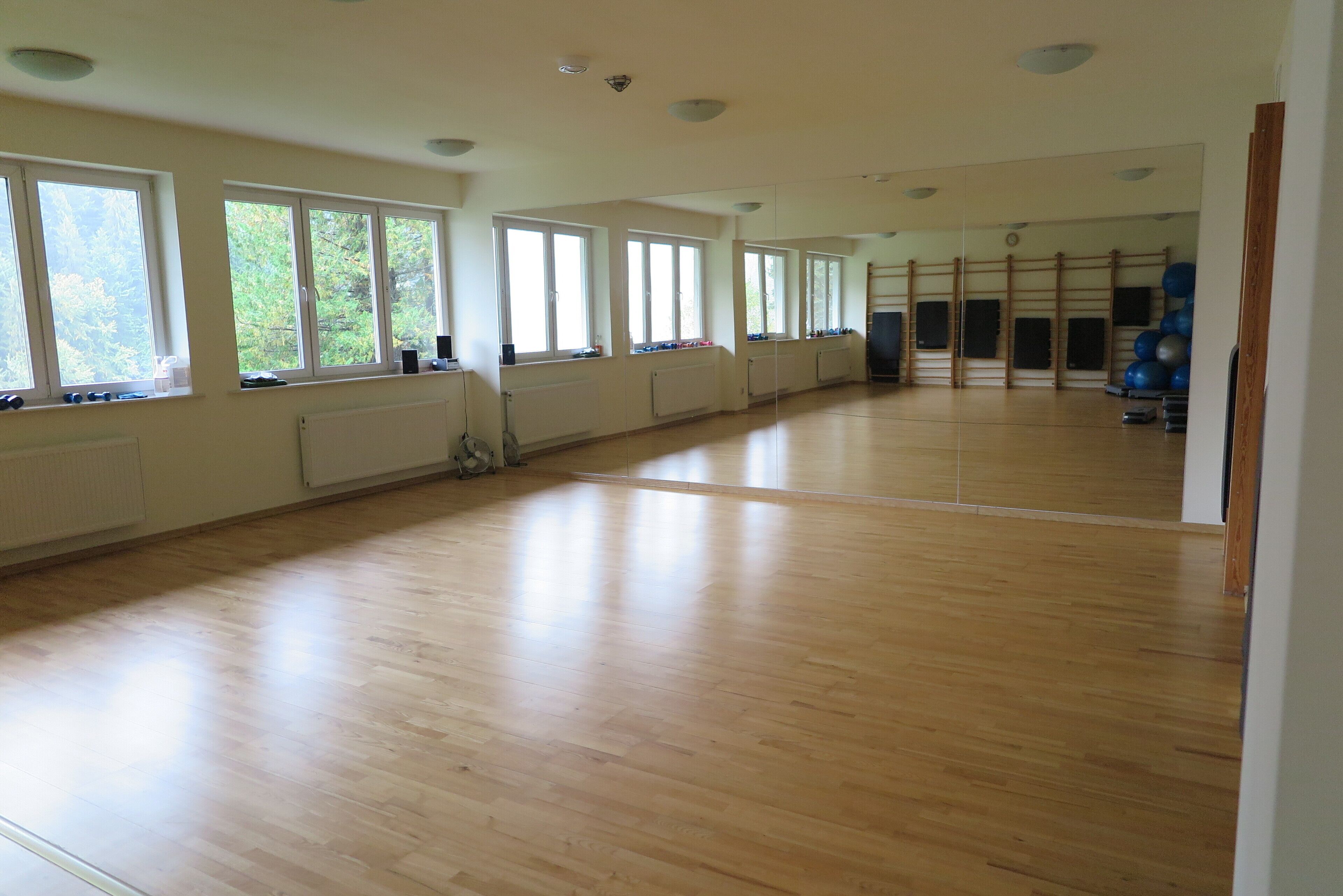 Una habitación amplia con ventanas grandes, suelo de madera y equipo de ejercicio.