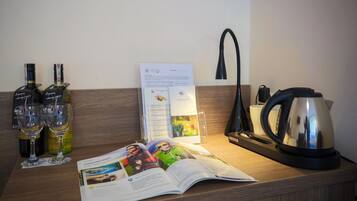 Una encimera de madera con dos botellas de vino, dos copas de vino, una revista, una tetera y una cafetera.