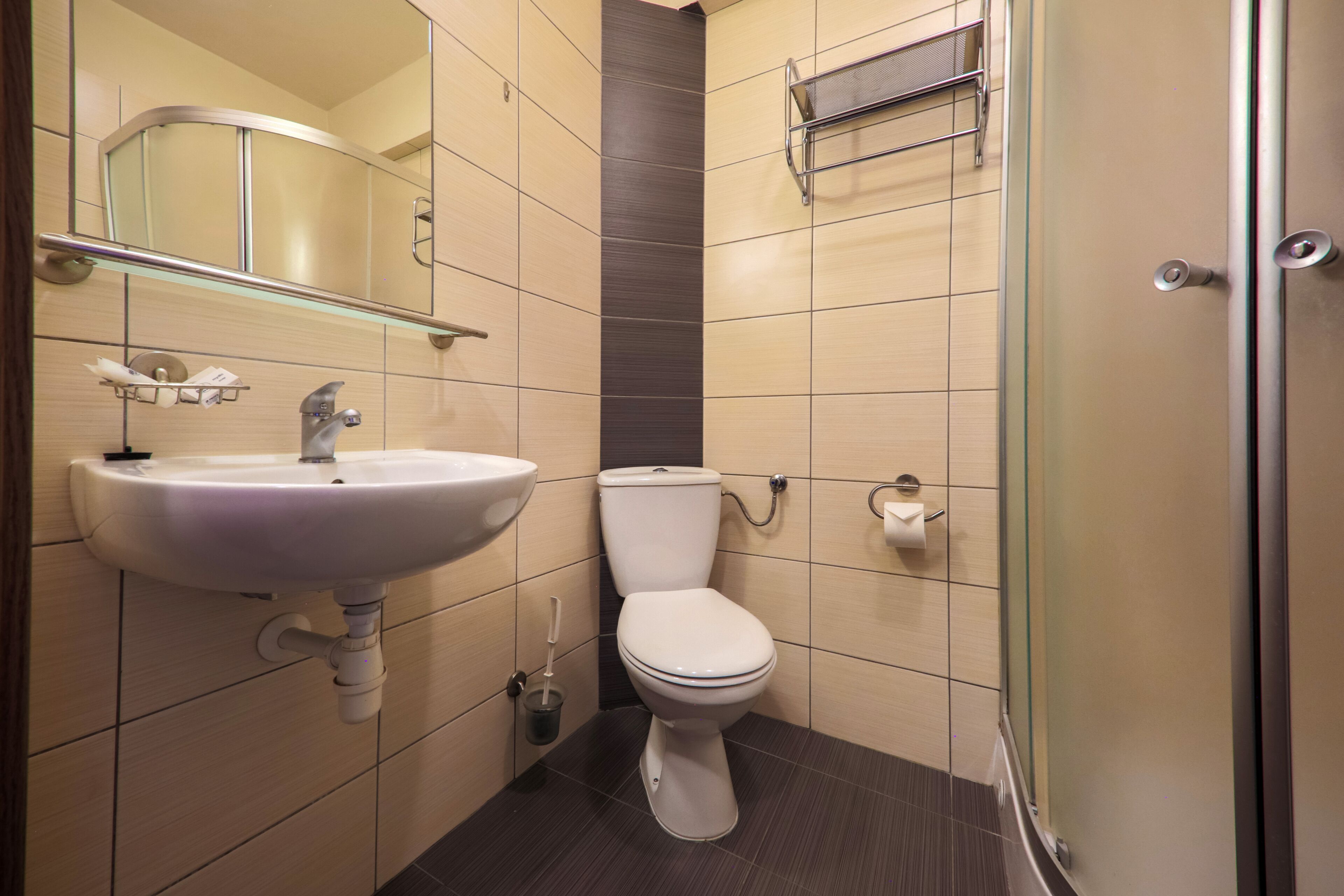 A modern bathroom with a white sink, a toilet, and a glass shower enclosure.