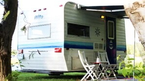 A mobile home with a 'shrimp' logo, a small deck with a table and chairs, and a door with a nautical-themed decoration. - Nautical Cozy camper trailer on Lake Simcoe (Orillia)