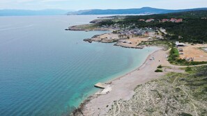 Una zona costera con playa, un pequeño poblado con casas y una vista despejada del mar.
