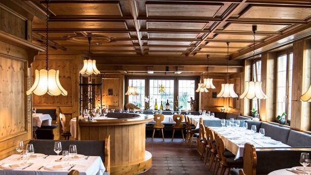A restaurant with wooden interiors, round tables, and hanging lamps. - Wirtshaus Zum Löwen (Steinenbronn)