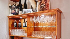 A wooden shelf with wine bottles, glasses, and decorative items including a deer head and a lamp. - Wirtshaus Zum Löwen (Steinenbronn)