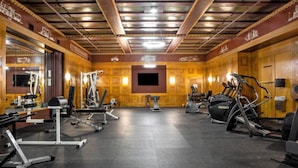 Una palestra con diverse attrezzature per esercizi, un grande specchio e uno schermo televisivo a parete.