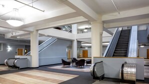 Un vestíbulo amplio con varios ascensores mecánicos, zonas de estar y un diseño arquitectónico moderno.