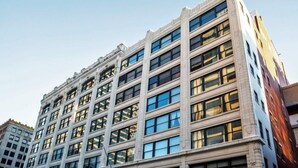 A multi-story building with a symmetrical facade, large windows, and a prominent corner entrance. - Contemporary 2BR 2BA Apartment In Downtown Indianapolis by CozySuites (Indianapolis)