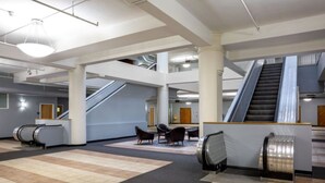 A spacious lobby with escalators, seating areas, and a central column. - Contemporary 2BR 2BA Apartment In Downtown Indianapolis by CozySuites (Indianapolis)