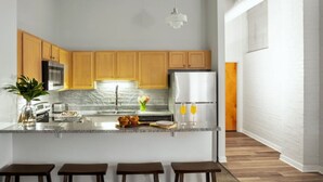 A modern kitchen with wooden cabinets, a marble countertop, and stainless steel appliances. - Contemporary 2BR 2BA Apartment In Downtown Indianapolis by CozySuites (Indianapolis)