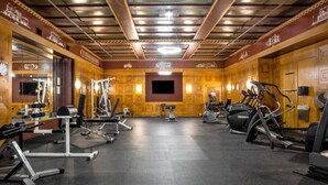 A gym with various exercise equipment, including treadmills and weight machines, and a large mirror on one wall. - TWO Bold 2BR 2BA Apartments by CozySuites (Indianapolis)