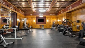 A gym with various exercise equipment, a large mirror, and a television screen. - TWO Urban 2BR 2BA Apartments by CozySuites (Indianapolis)