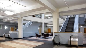 A spacious lobby with escalators, seating areas, and a modern architectural design. - TWO Urban 2BR 2BA Apartments by CozySuites (Indianapolis)