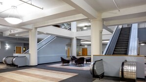 A spacious lobby with escalators, seating areas, and a modern architectural design. - BOLD 2BR/2BA In The Block Apartment by CozySuites (Indianapolis)