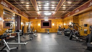 A gym with various exercise equipment, including treadmills and weight machines, and a large mirror on the left wall. - BOLD 2BR/2BA In The Block Apartment by CozySuites (Indianapolis)