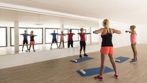 A spacious gym with large windows, wooden floors, and blue exercise mats. - Aparthotel Ciudad Laurel (Son Servera)