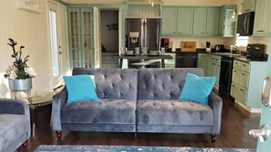 A living room with a grey sofa, blue cushions, and a patterned rug. - 🧜‍♀️ Oasis Paradise Guesthouse (Granbury)