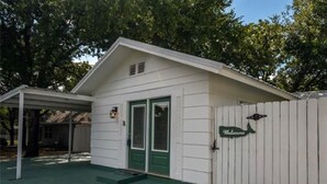 A single-story building with a green door and a 'Welcome' sign on the white picket fence. - 🧜‍♀️ Oasis Paradise Guesthouse (Granbury)