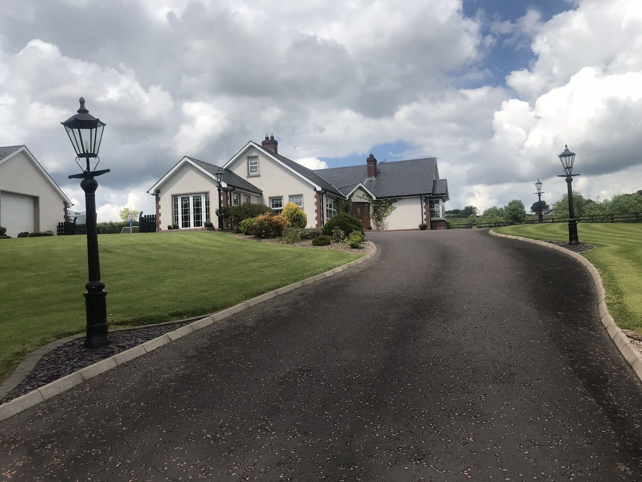 A residential street with houses, a curved driveway, and street lamps.