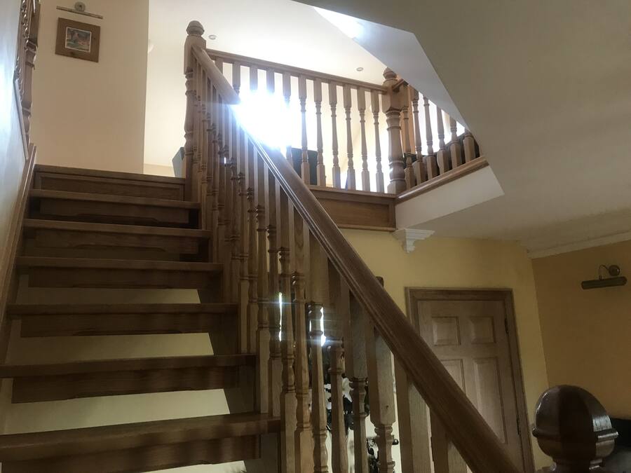 A wooden staircase with a handrail, leading to an upper level.