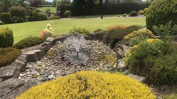 A garden with a water feature, surrounded by various shrubs and a lawn.