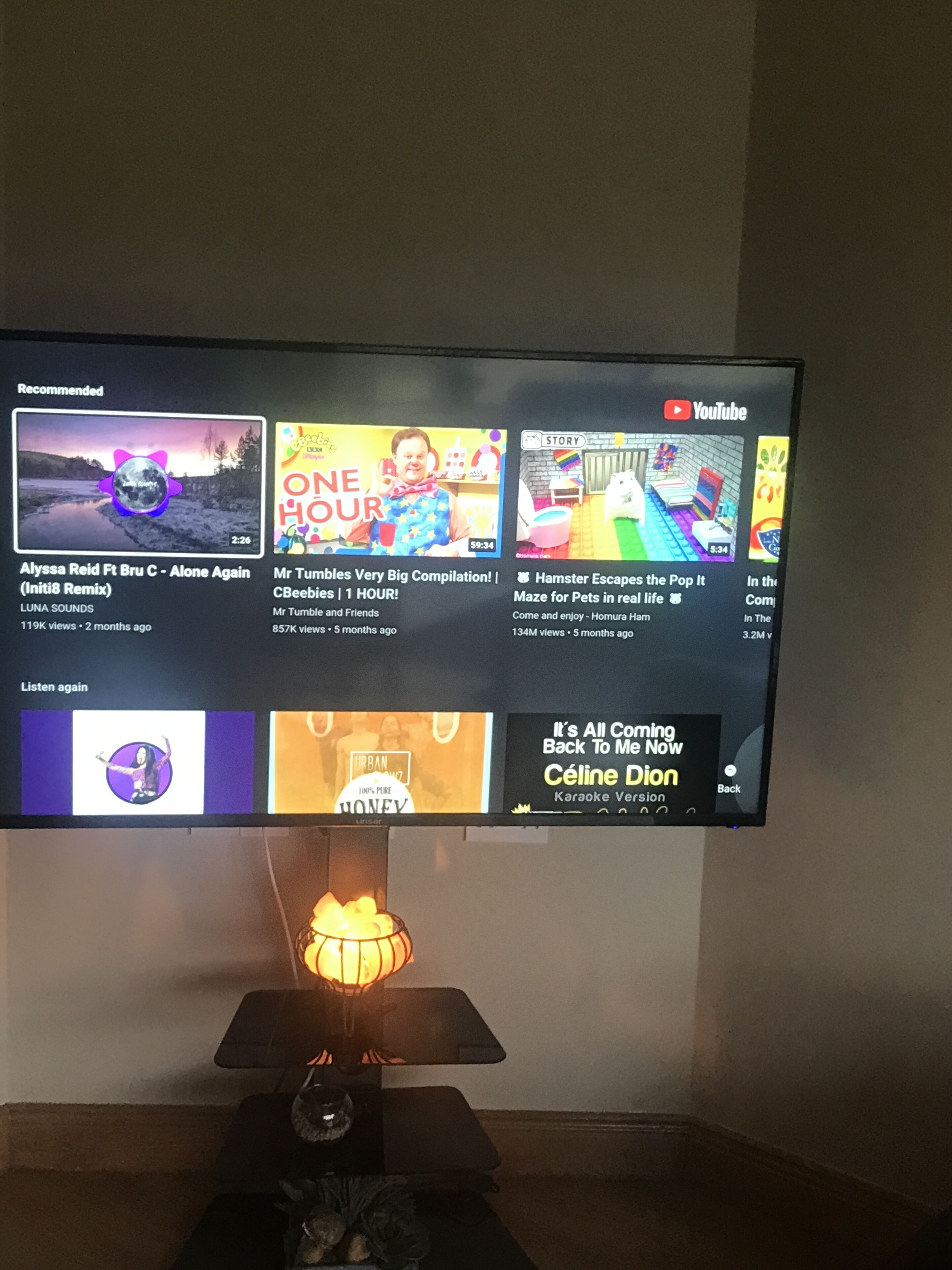 A television displaying a YouTube interface with various video thumbnails and titles.