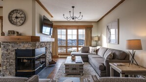 Un salón acogedor con chimenea de piedra, un ventanal con vistas, un sofá y una televisión.