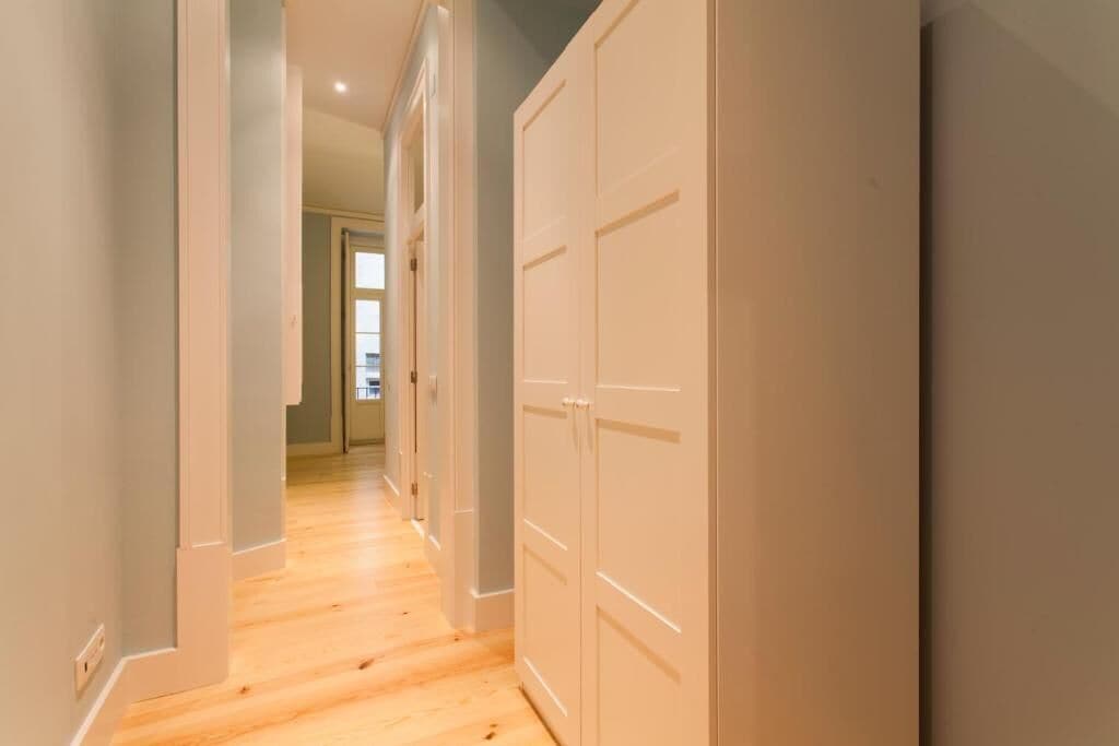 Un pasillo con suelo de madera y puertas blancas.