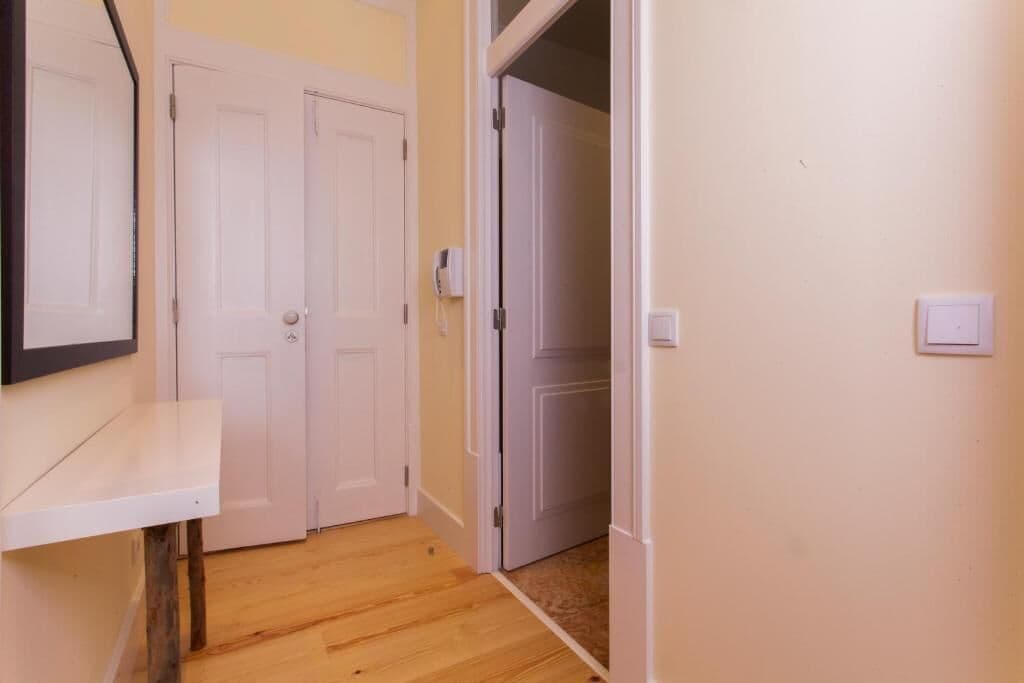 Un couloir avec un plancher en bois, des portes blanches et un mur blanc.