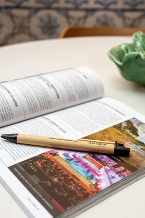Un libro con un bolígrafo encima, una fotografía y un adorno verde.
