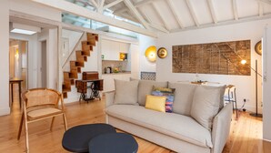 A spacious living area with a high ceiling, a sofa, a wooden chair, and a dining table. - Casas da Baixa - Jules & Madeleine (Lisbon)