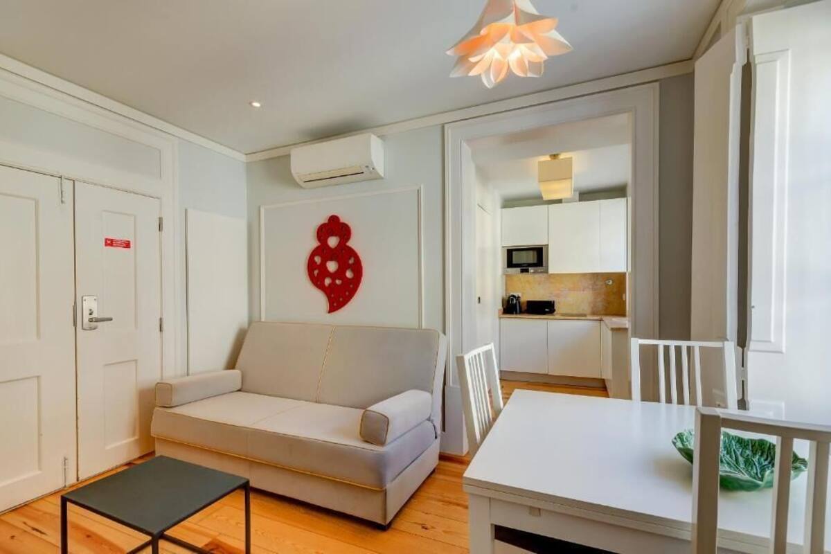 A modern living room with a sofa, a dining table, and a kitchen in the background.