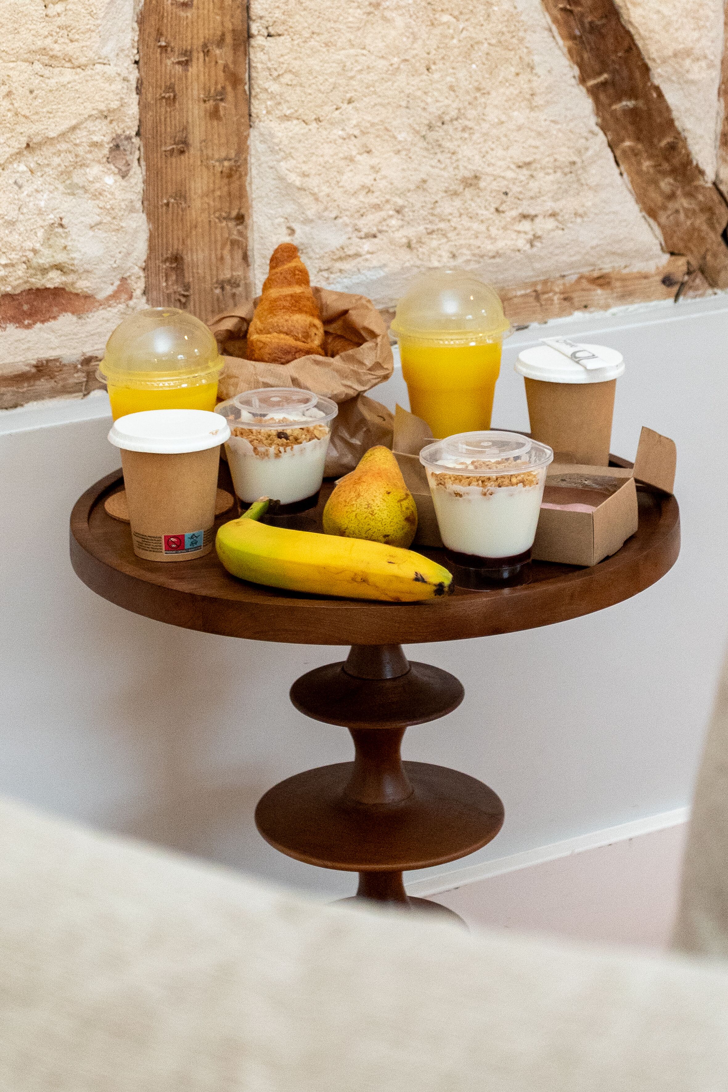 Un plateau contenant de la nourriture et des boissons, notamment une banane, une poire, un yaourt et du jus de fruits.