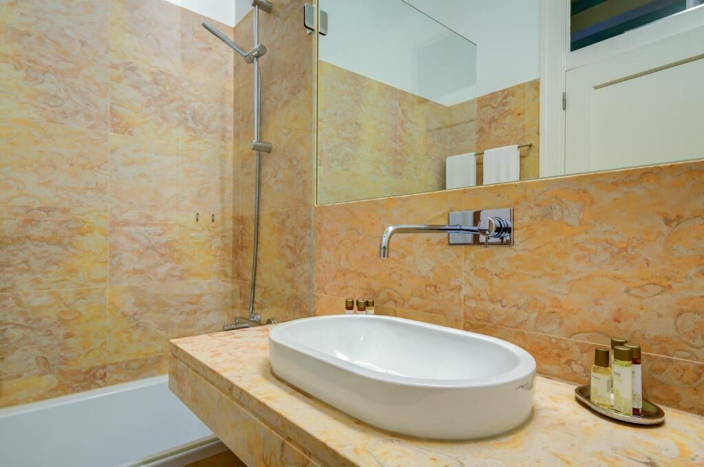 Ein Badezimmer mit einem großen, ovalen Waschbecken, einer Dusche und einem Spiegel über dem Waschbecken.