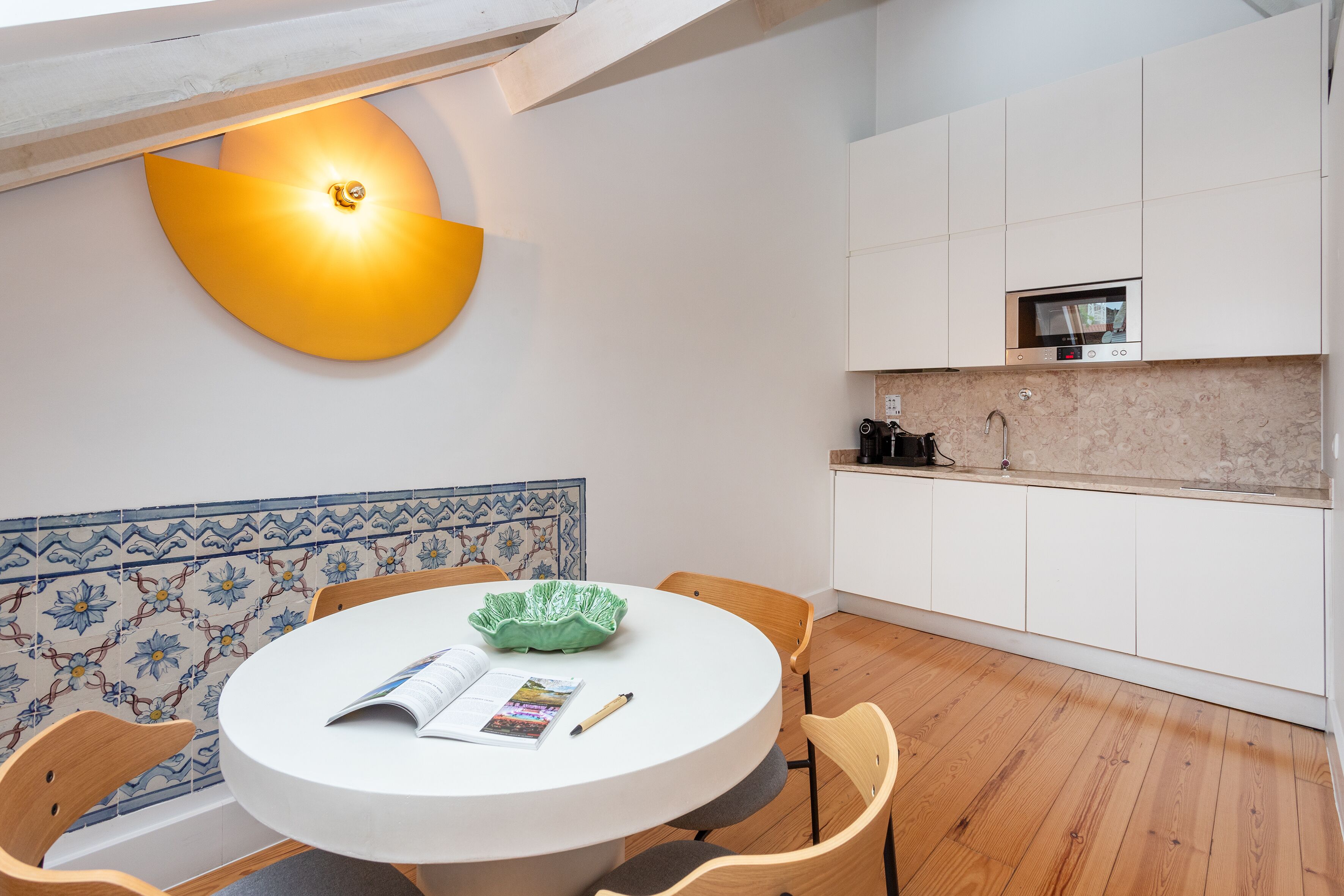 A modern kitchen with white cabinets, a built-in microwave, and a wooden floor.