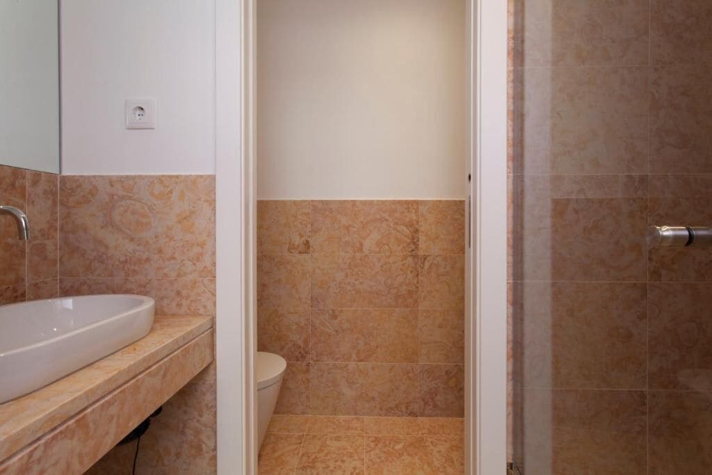 Un baño con lavamanos blanco, inodoro y zona de ducha.