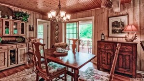 Un intérieur en bois comprenant une table à manger, des chaises, un lustre et des meubles de rangement.