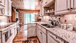 Une cuisine avec des meubles en bois, un plan de travail en marbre et un pare-feu en carreaux.
