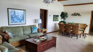 A living room with a green sofa, wicker furniture, a wooden coffee table, and a ceiling fan. - Beautiful Waterfront Large Private Gulfside Home Family Friendly.  (Marathon)