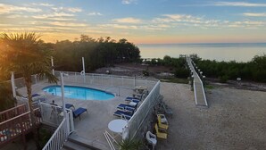 A pool area with lounge chairs and a view of the sea at sunset. - Beautiful Waterfront Large Private Gulfside Home Family Friendly.  (Marathon)