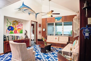 A room with a blue patterned floor, wooden furniture, a ceiling fan, and a large fish mural on the wall. - Vacation Rental Redefined, St. George's Caye Belize (Belize City)