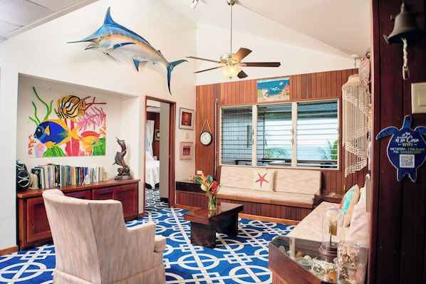 A room with a blue patterned floor, wooden furniture, a ceiling fan, and a large fish mural on the wall. - Vacation Rental Redefined, St. George's Caye Belize (Belize City)