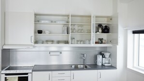 A modern kitchen with white cabinetry, a stainless steel sink, and a built-in oven. - Nuuk Hotel Apartments by HHE (Nuuk)