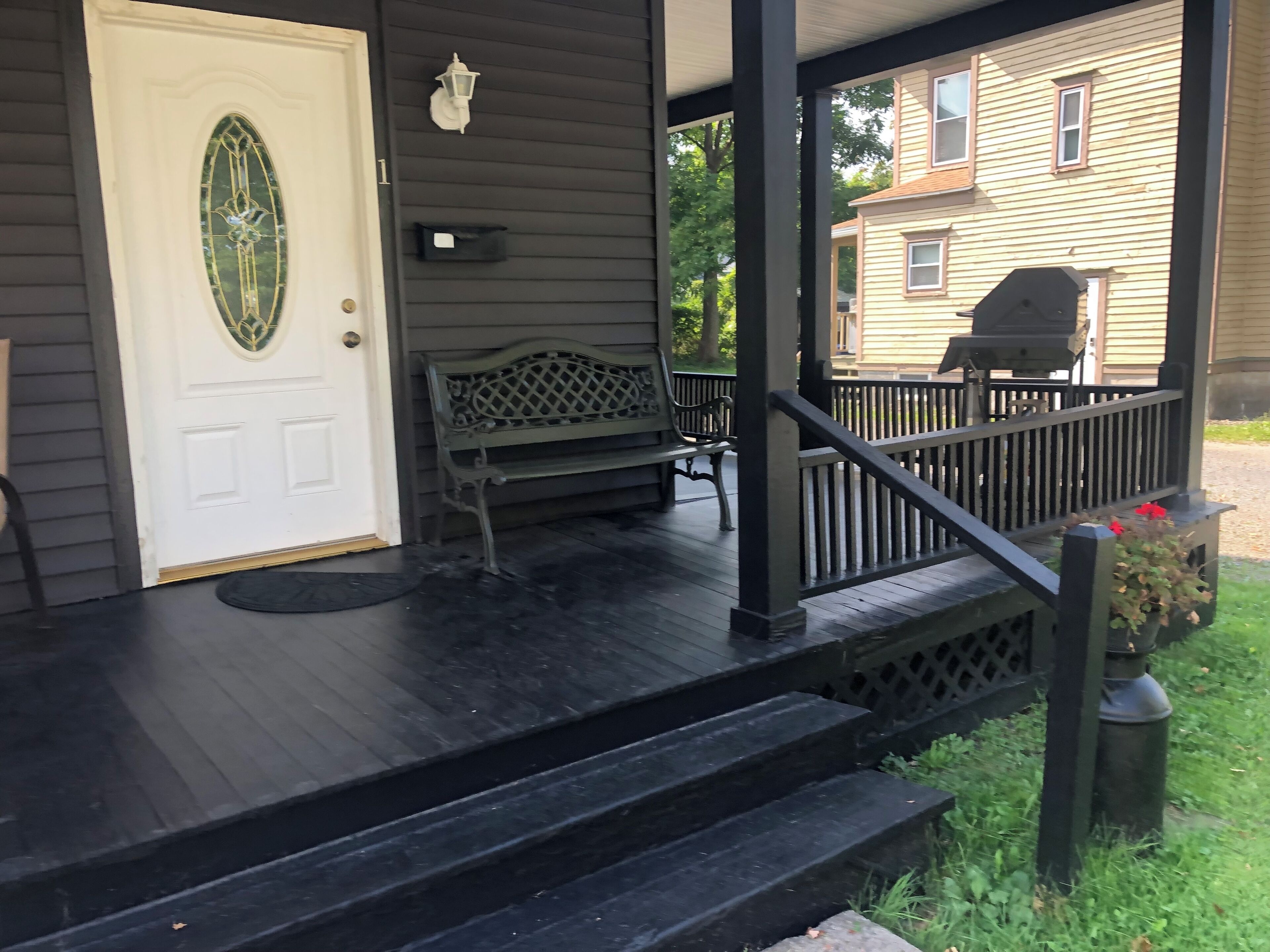 A porch with a bench, a mailbox, and a door with a decorative glass panel.