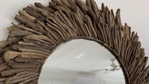 A round mirror with a rustic wooden frame, reflecting a room with a bed, two lamps, and a painting on the wall. - Beautiful Beachfront Apartment: Turtles Nest B (Dover)