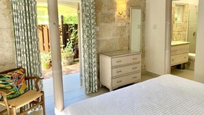 A bedroom with a bed, a dresser, a mirror, and a view of the outside. - Beautiful Beachfront Apartment: Turtles Nest B (Dover)