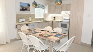 A modern kitchen with a dining area, featuring a wooden table, white wicker chairs, and pendant lighting. - Beautiful Beachfront Apartment: Turtles Nest B (Dover)