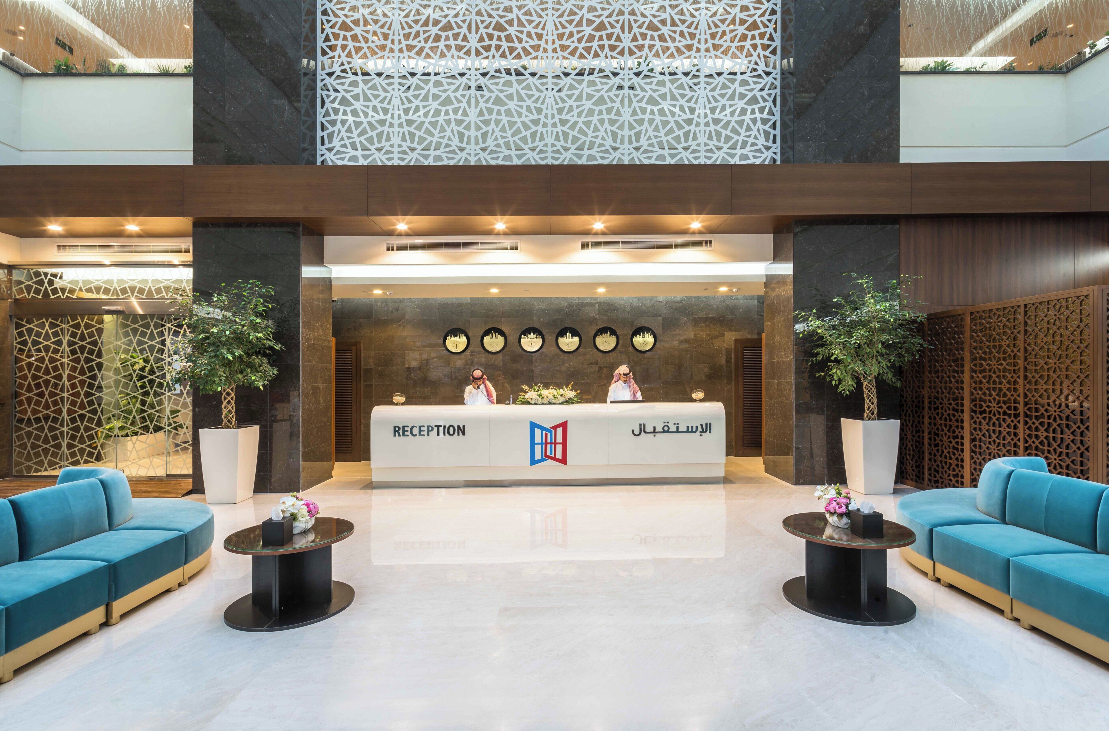 A reception area with a reception desk, two sofas, and potted plants.
