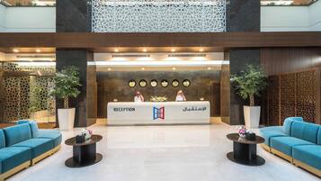 A reception area with a reception desk, two sofas, and potted plants.