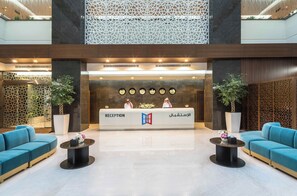 A reception area with a reception desk, two sofas, and potted plants.