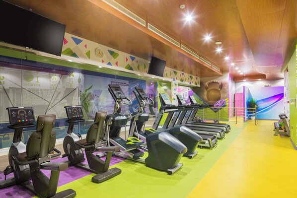 Una palestra con tapis roulant, cyclette e un'ampia parete orologiera.