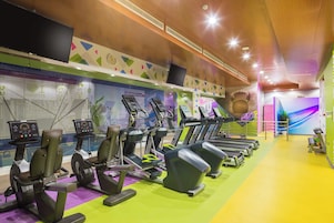A gym with treadmills, exercise bikes, and a large wall clock.